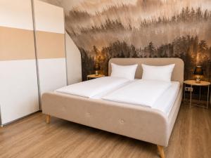 a bed in a bedroom with a painting on the wall at PrimeLoft Apartments am Kurpark in Braunlage