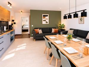 a kitchen and living room with a large wooden table at PrimeLoft Apartments am Kurpark in Braunlage