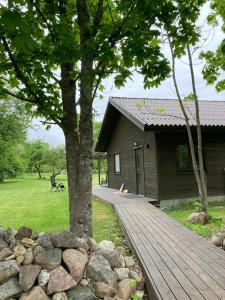 a wooden walkway leading to a house with a tree at Aru talu külalistemaja in Iilaste