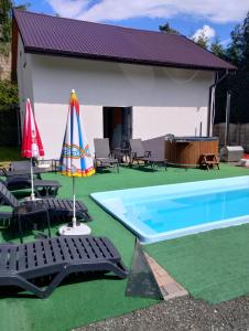 a pool with two lawn chairs and an umbrella at Apartament u Wioli in Okleśna