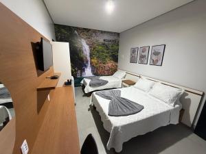a room with two beds and a tv in it at Alphaville Hotel in Barra do Bugres