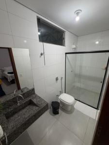 a bathroom with a toilet and a shower and a sink at Alphaville Hotel in Barra do Bugres