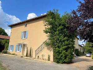 a large tree next to a house with a staircase at Gite de la vallée in Rochechouart