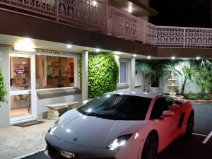 曼杜拉的住宿－曼哲拉福瑞肖爾汽車旅館，停在大楼前的白色和红色的汽车