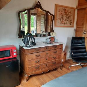 a bedroom with a dresser with a mirror and a microwave at Chambre d'hôte Le Châtaignier in Planchez