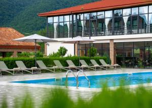 a pool with chairs and umbrellas in front of a building at In Gremi Hotel in Gremi