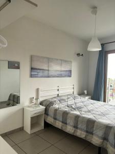 a white bedroom with a bed and a window at Taormina Belu Beach Apartment in Letojanni