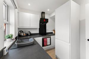 a kitchen with white cabinets and a black counter top at Spacious Modern 2BR - Parking - Workspace Area, Ideal for Contractors & Long Stays - NordStay in Amley +12 photos