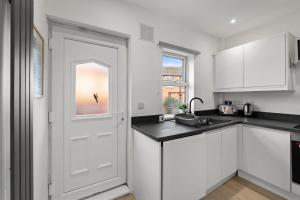 a kitchen with white cabinets and a white door at Spacious Modern 2BR - Parking - Workspace Area, Ideal for Contractors & Long Stays - NordStay in Amley
