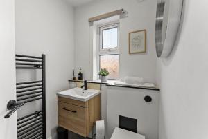 a white bathroom with a sink and a window at Spacious Modern 2BR - Parking - Workspace Area, Ideal for Contractors & Long Stays - NordStay in Amley