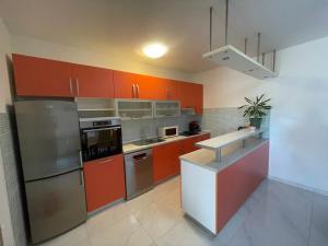 a kitchen with orange cabinets and a stainless steel refrigerator at Nany-Villa with heated pool in Trolokve