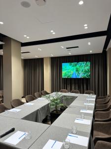 a conference room with tables and chairs and a large screen at Mulaj Hotel in Tirana