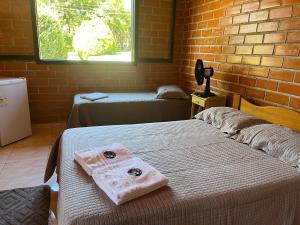a room with two beds and a brick wall at Bella Vite in São José dos Pinhais