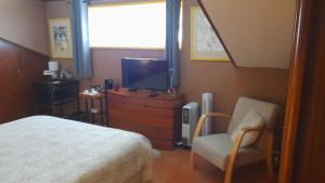 a bedroom with a bed and a tv and a chair at Casa Amarela in Esmoriz