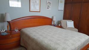 a bedroom with a large bed and a chair at Casa Amarela in Esmoriz
