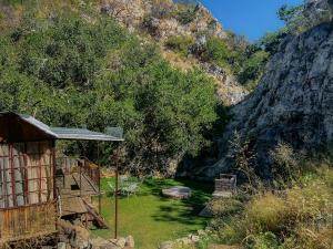 a small house with a grassy yard next to a mountain at Glocke Mountain Camp, Cabin in Outjo