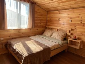 a bed in a log cabin with a window at Welcome to Карпати in Skole +56 photos