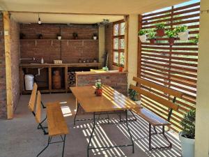 a patio with a table and a bench and a kitchen at Brvnara Bata - Vikendica na Drini in Lipnički Šor +33 photos