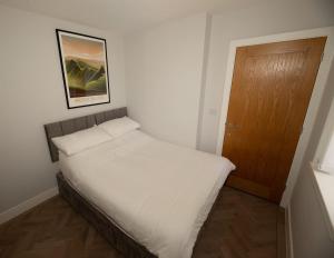 a bedroom with a bed and a wooden door at The Loft Town Centre in Merthyr Tydfil