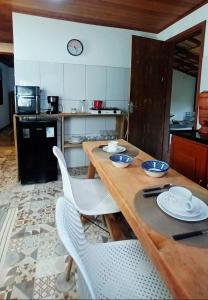 a kitchen with a wooden table and chairs and a kitchen with a refrigerator at Casa Águas do Céu de Lumiar in Nova Friburgo +9 photos