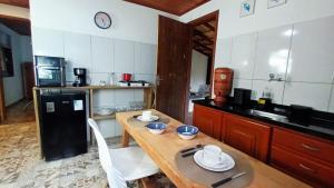 a kitchen with a wooden table and a black refrigerator at Casa Águas do Céu de Lumiar in Nova Friburgo