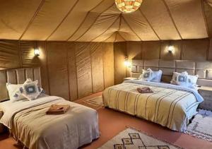two beds in a room with a tent at Shining Luxury Camp in Merzouga