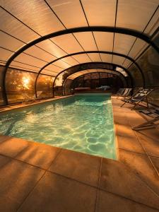 an indoor swimming pool with an archway and chairs at Chic et Charme Cottage in Suzay