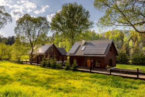 a house with solar panels on it in a field at Chaty Rysia i Misia - całoroczne domy na wynajem in Wetlina
