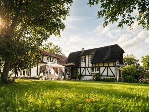 a white house with a black roof on a green field at Chic et Charme Cottage in Suzay