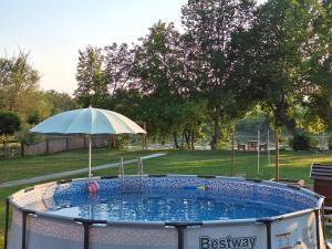 a hot tub with an umbrella in a park at Brvnara Bata - Vikendica na Drini in Lipnički Šor