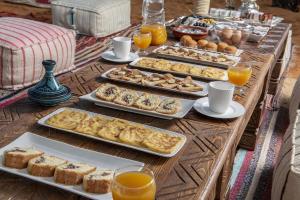 a table topped with trays of pastries and orange juice at Shining Luxury Camp in Merzouga +23 photos