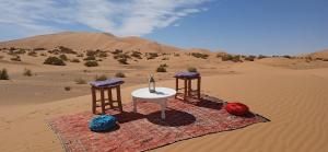 a table and two chairs in the desert at Shining Luxury Camp in Merzouga