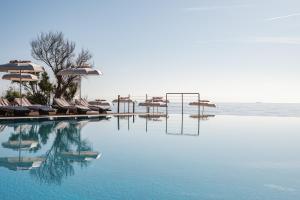 a swimming pool with chairs and umbrellas in the water at La Villa Del Re - Adults Only - Small Luxury Hotels of the World in Castiadas