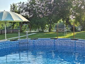 a swimming pool with an umbrella and an umbrella at Brvnara Bata - Vikendica na Drini in Lipnički Šor