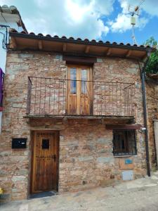 an old stone house with a balcony and two doors at El Silencio in Mesegal