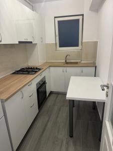 a kitchen with white cabinets and a sink and a table at Otopeni Maramures in Otopeni