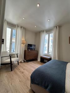 a bedroom with a bed and a chair and windows at La suite de Elise in Beaulieu-sur-Mer