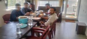 a group of men sitting at a table eating food at Prithivee Homestay in Kotagiri +34 photos