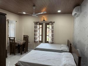 a bedroom with two beds and a table and a ceiling fan at Velu House - 2-Room Apartment in Jaffna
