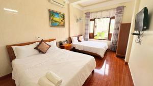 a hotel room with two beds and a television at Hoa Phuong Hotel Phong Nha in Phong Nha