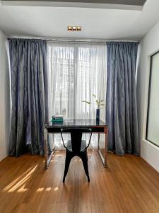 a desk in front of a window with curtains at The Hermitage Tagaytay-Presidential Suite in Malabag