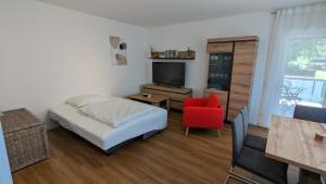 a small bedroom with a bed and a red chair at Rudolph Apartments Kleve in Kleve