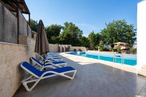 a group of chairs and an umbrella next to a swimming pool at Apartments Rajsko Mjesto in Tivat