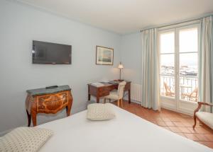 a hotel room with a desk and a television at hôtel Sube in Saint-Tropez