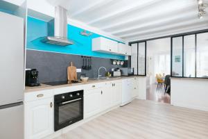 a kitchen with white cabinets and a blue wall at Le Triplex du Vœu Spacious Apartment in Cherbourg en Cotentin