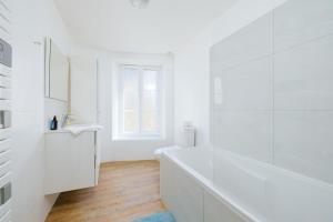 a white bathroom with a tub and a window at Le Triplex du Vœu Spacious Apartment in Cherbourg en Cotentin
