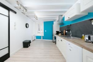 a kitchen with white cabinets and blue walls at Le Triplex du Vœu Spacious Apartment in Cherbourg en Cotentin +13 photos