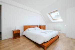 a bedroom with a large white bed and a skylight at Le Triplex du Vœu Spacious Apartment in Cherbourg en Cotentin