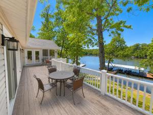 a porch with a table and chairs and a view of a lake at The Ozark Acre 6BDR Lakefront in Sunrise Beach