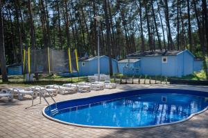 a large swimming pool with chairs and a building at Greckie Domki ZEUS in Stegna